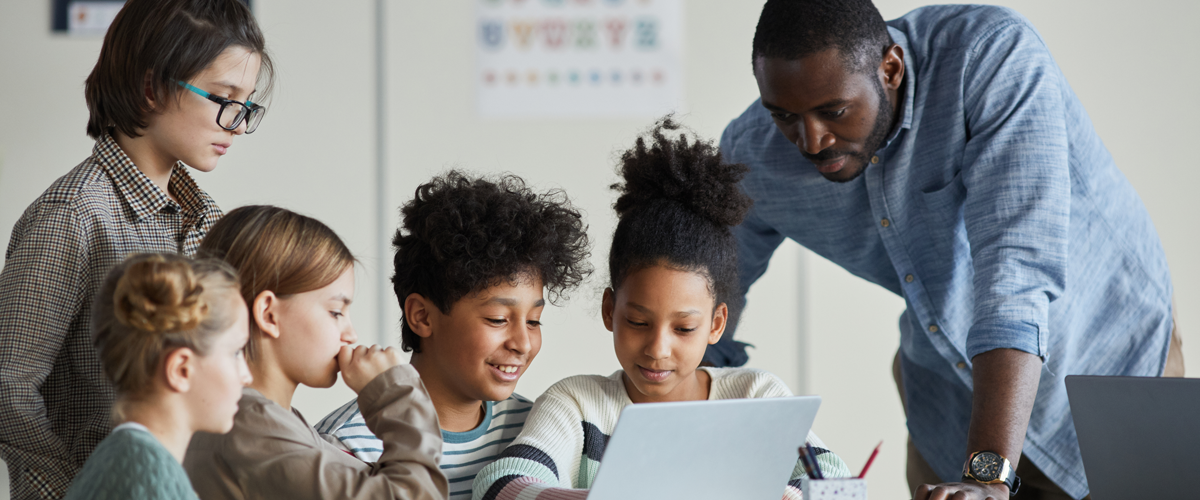 Teacher helping a group of students work together in a classroom