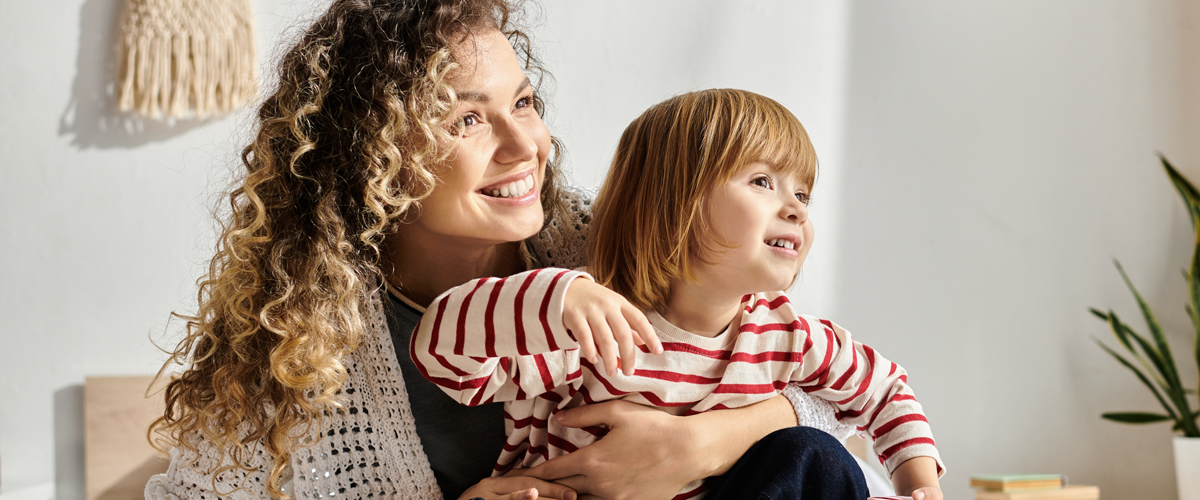 Parent smiling with a young child seated on her lap
