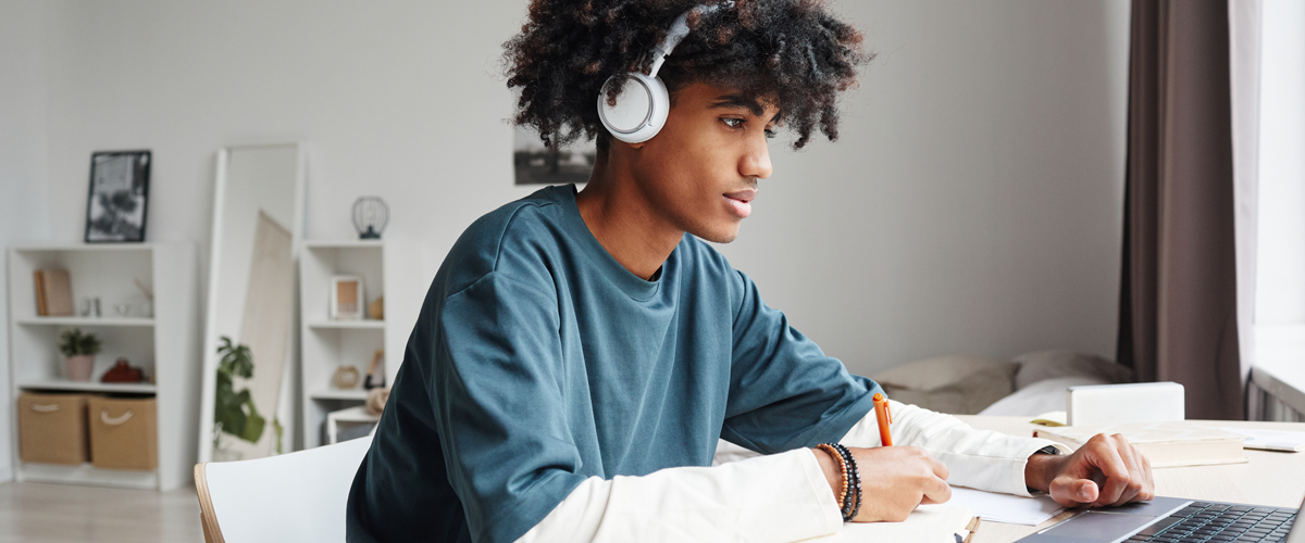 Student wearing headphones while working on an assignment at a desk